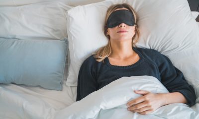 Portrait of traveler woman relaxing and peacefully sleeping with sleep mask at hotel room. Travel concept.